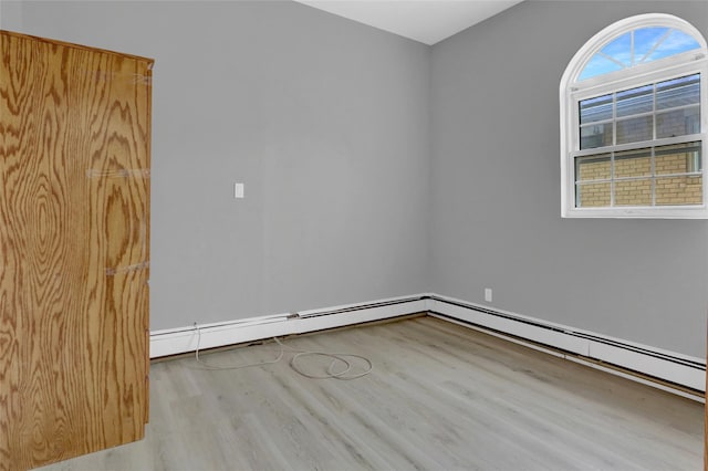 spare room with baseboards, baseboard heating, and wood finished floors