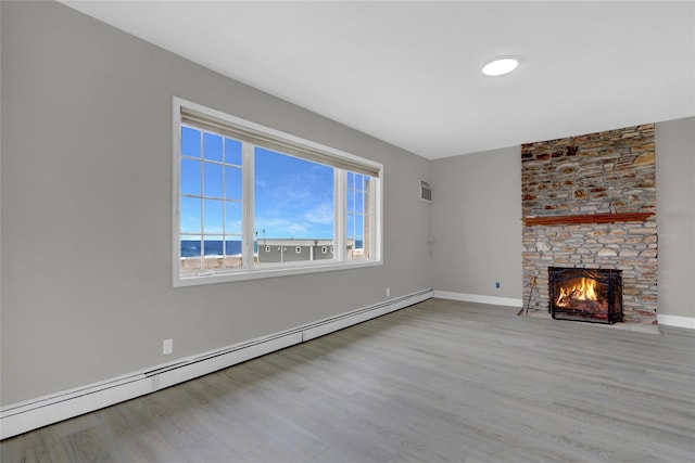unfurnished living room with wood finished floors, visible vents, a fireplace, baseboard heating, and baseboards