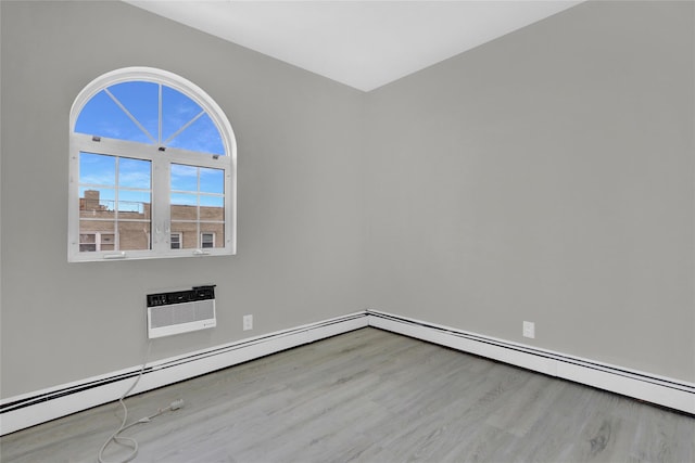 unfurnished room with a wall mounted air conditioner, wood finished floors, and a baseboard heating unit