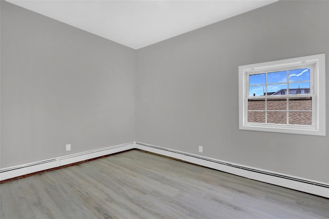 empty room featuring baseboards, a baseboard radiator, and wood finished floors