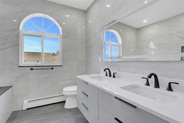 bathroom with a sink, tile walls, toilet, and baseboard heating