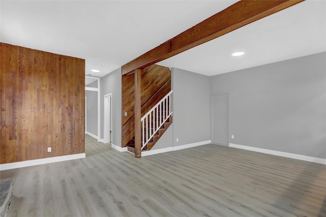 unfurnished living room featuring recessed lighting, wood finished floors, baseboards, and stairs