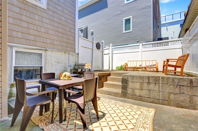 view of patio / terrace featuring fence, outdoor dining area, and a grill