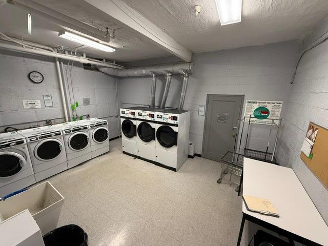 shared laundry area with washing machine and clothes dryer, concrete block wall, and tile patterned floors