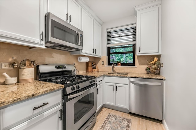 52 Rockledge Rd Unit 2A, Hartsdale, NY 10530 - kitchen featuring appliances with stainless steel finishes, a sink, light wood-style flooring, white cabinets, and decorative backsplash