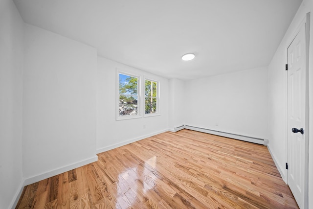 unfurnished bedroom with baseboards, wood finished floors, and baseboard heating