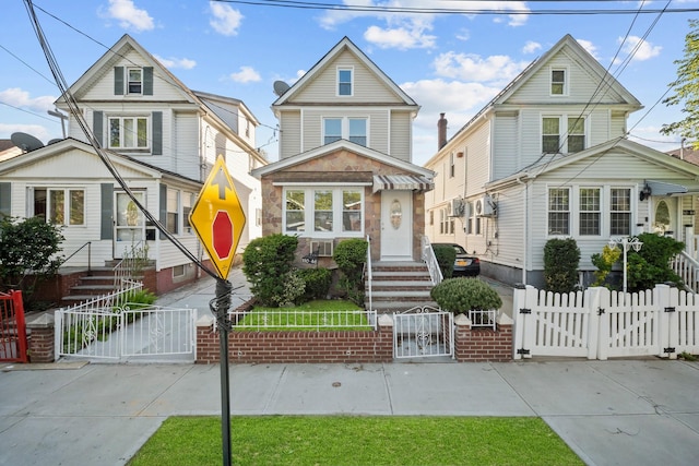 view of front of property featuring entry steps, a fenced front yard, and a gate