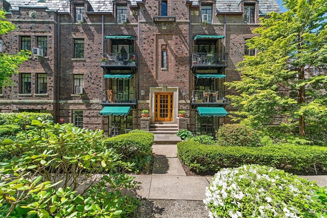 entrance to property featuring brick siding, a high end roof, and cooling unit