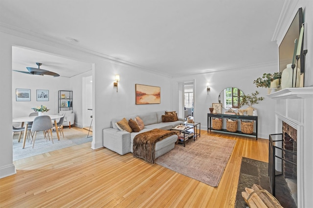 living area featuring light wood finished floors, ornamental molding, a fireplace with flush hearth, and baseboards