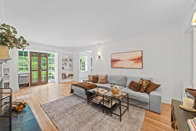 living room featuring crown molding, built in features, light wood-style floors, healthy amount of natural light, and a fireplace