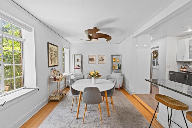 dining space featuring light wood finished floors, ceiling fan, and baseboards