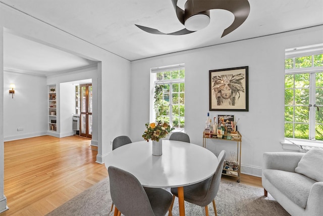 dining space featuring crown molding, ceiling fan, light wood-style flooring, and baseboards