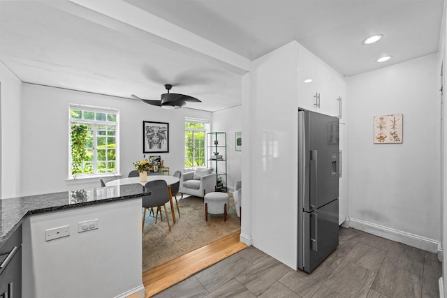 kitchen with stainless steel fridge with ice dispenser, healthy amount of natural light, white cabinetry, dark stone counters, and recessed lighting
