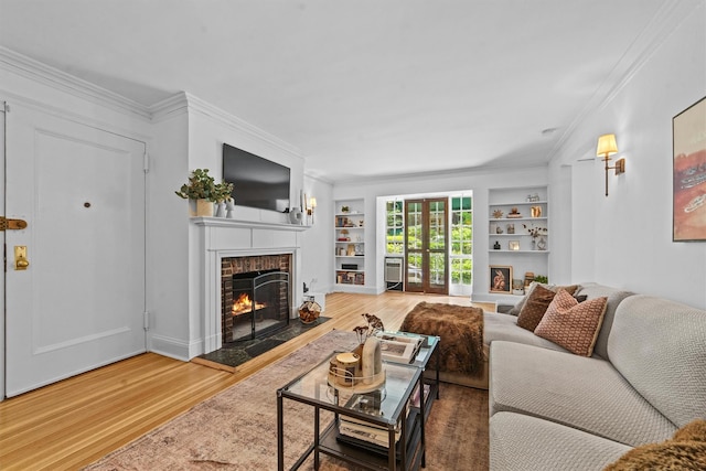 living room featuring a fireplace, wood finished floors, built in shelves, ornamental molding, and baseboards