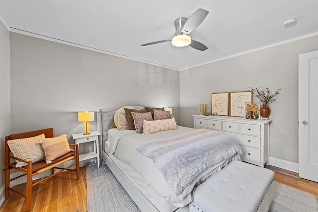 bedroom featuring crown molding, light wood-style floors, baseboards, and a ceiling fan