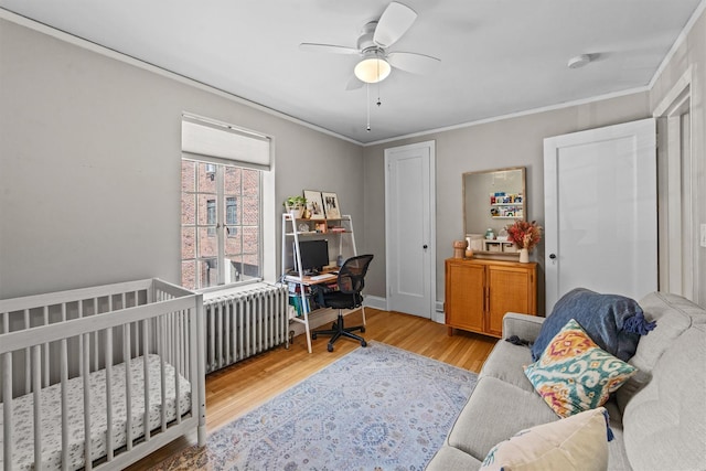 bedroom with wood finished floors, an office area, ornamental molding, and ceiling fan