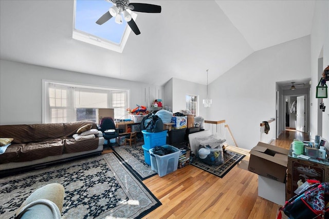 living area featuring wood finished floors, a skylight, ceiling fan, and high vaulted ceiling