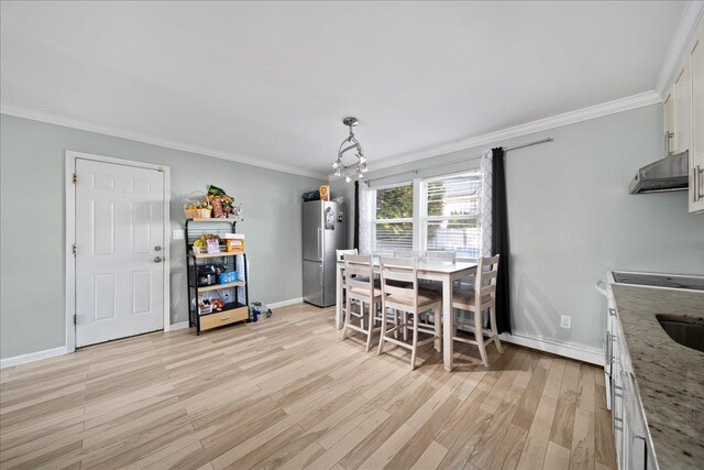 dining area with light wood finished floors, crown molding, baseboards, and a notable chandelier
