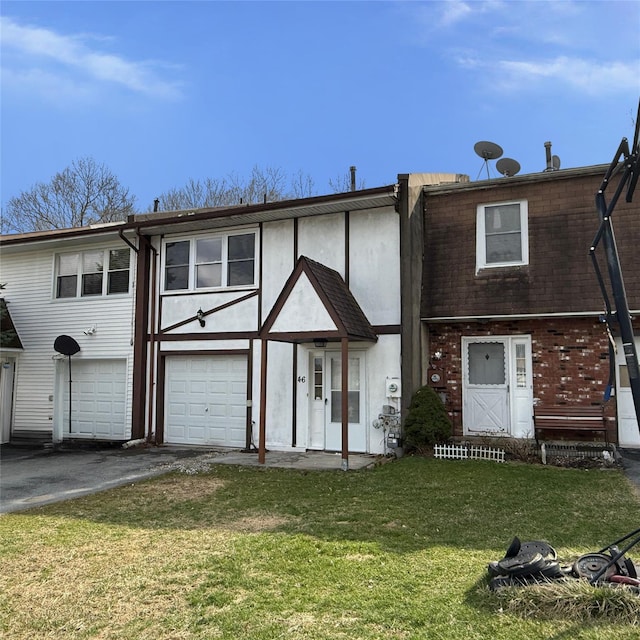 view of front facade featuring an attached garage, brick siding, a front yard, and aphalt driveway