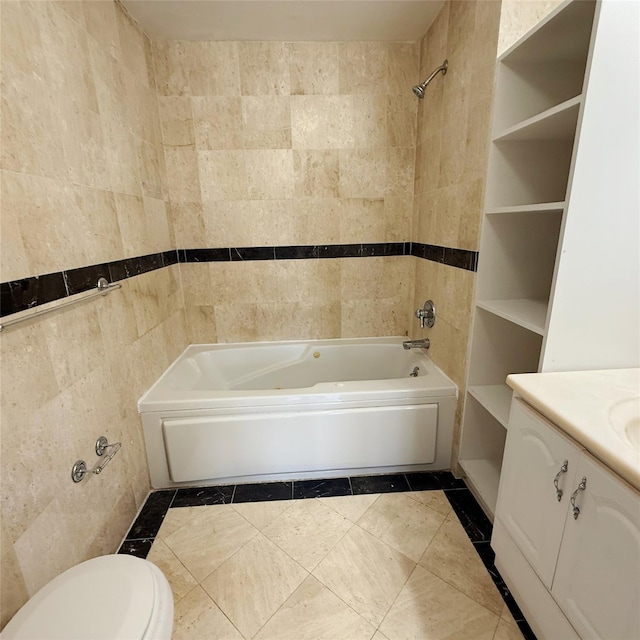 bathroom featuring tile walls, toilet, vanity, tile patterned flooring, and bathing tub / shower combination