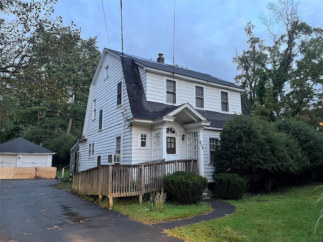 colonial inspired home with a gambrel roof, a chimney, a wooden deck, and cooling unit