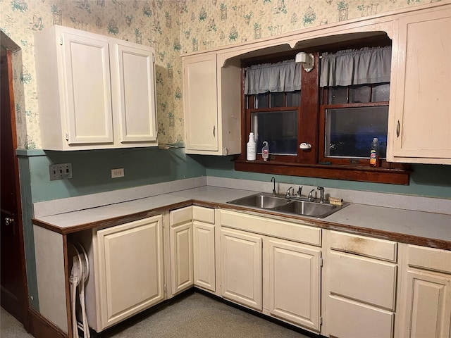 kitchen featuring wallpapered walls, light countertops, and a sink