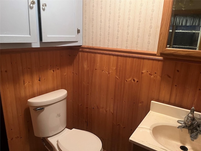 bathroom featuring wallpapered walls, toilet, wood walls, and vanity