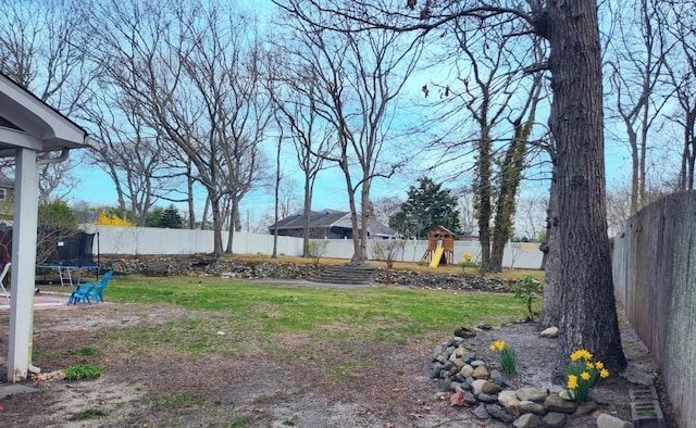 view of yard featuring a fenced backyard, a trampoline, and a playground