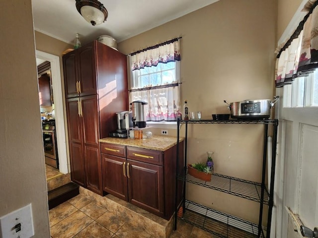 kitchen featuring stainless steel range with gas stovetop, a wealth of natural light, and light stone counters