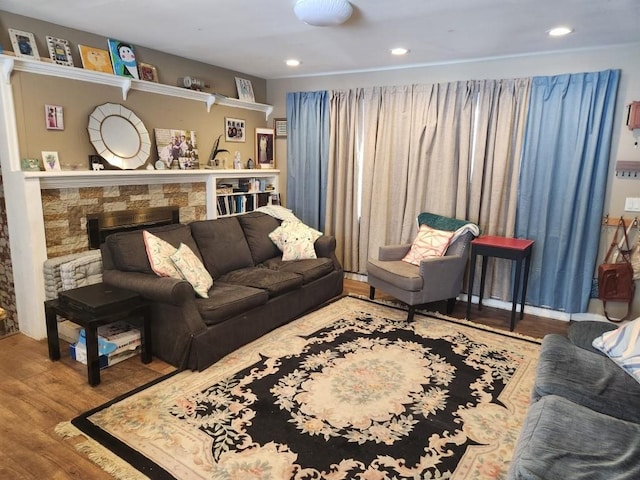 living room featuring wood finished floors, a stone fireplace, and recessed lighting