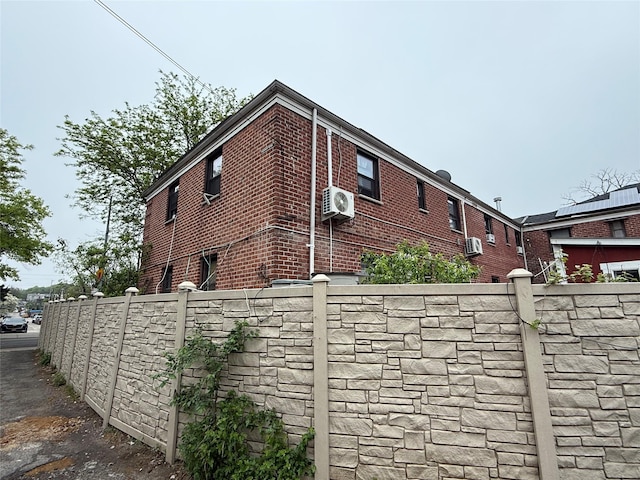 view of property exterior with brick siding and fence