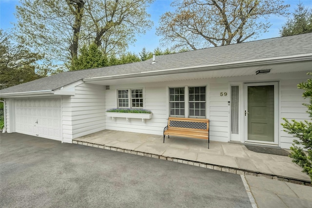 exterior space with driveway, a shingled roof, and a garage