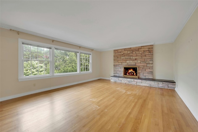 unfurnished living room featuring a fireplace, ornamental molding, baseboards, and wood finished floors