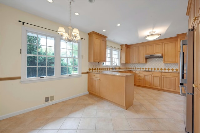 kitchen featuring a peninsula, freestanding refrigerator, visible vents, an inviting chandelier, and backsplash