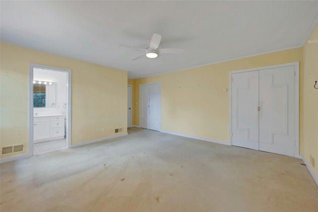 unfurnished bedroom with baseboards, light carpet, multiple closets, and visible vents
