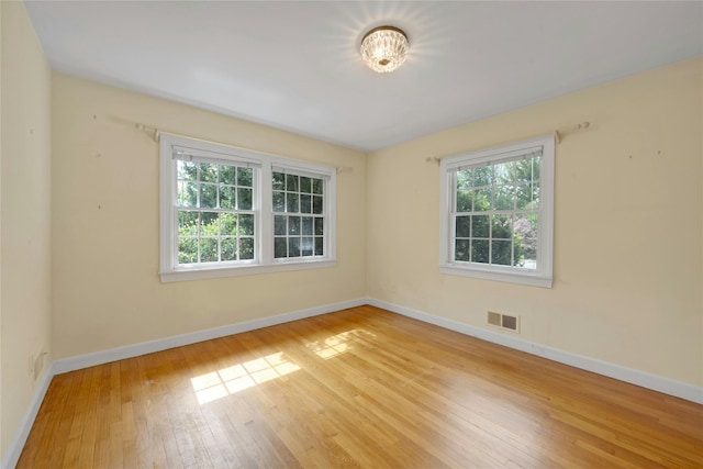spare room featuring visible vents, baseboards, and hardwood / wood-style flooring