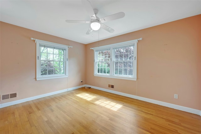 unfurnished room with a ceiling fan, visible vents, light wood-style flooring, and baseboards