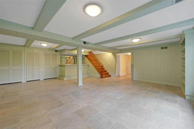 finished below grade area with visible vents, tile patterned flooring, baseboards, and stairs