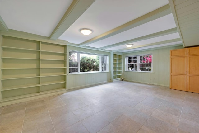 unfurnished room with beam ceiling, built in features, light tile patterned floors, and wooden walls