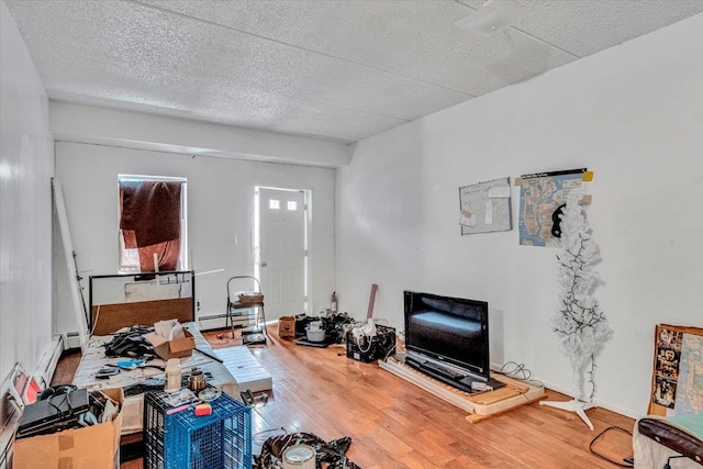 living area featuring a textured ceiling, baseboard heating, and wood finished floors
