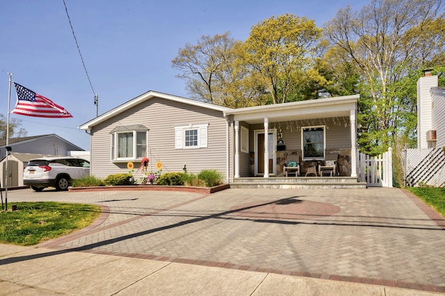 view of front facade with an outbuilding, fence, decorative driveway, a porch, and a storage shed