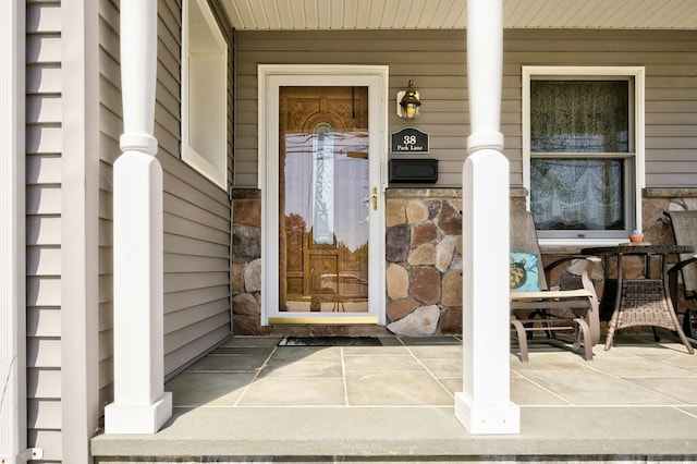 view of exterior entry with stone siding and a porch