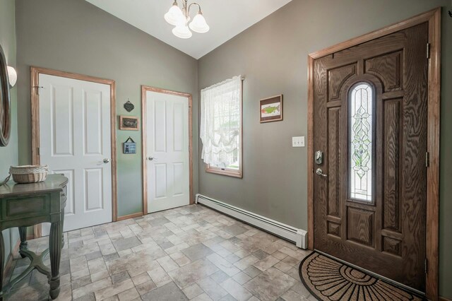 entryway featuring lofted ceiling, a notable chandelier, baseboard heating, and stone finish flooring