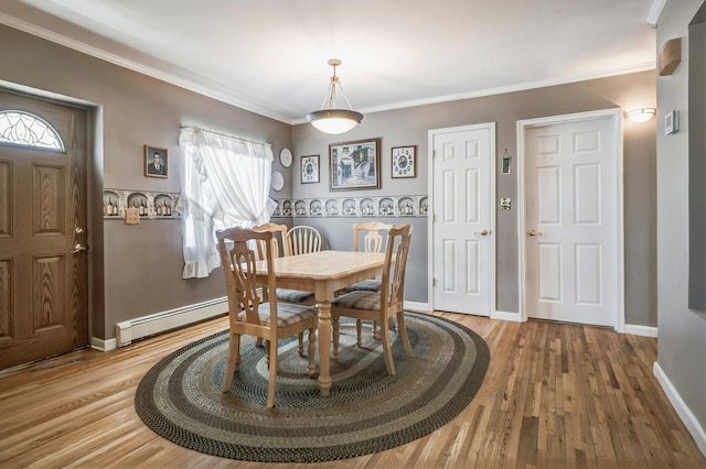 dining space with crown molding, baseboard heating, and wood finished floors