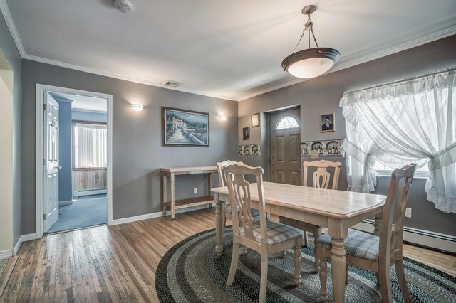 dining room featuring a baseboard radiator, baseboards, visible vents, crown molding, and wood finished floors