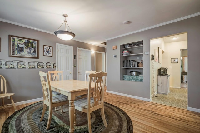 dining area with baseboards, light wood-style flooring, crown molding, and built in features