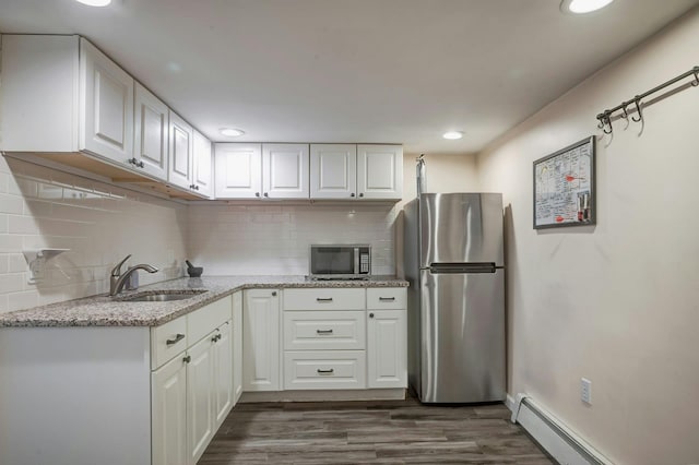 kitchen with a sink, stainless steel appliances, backsplash, dark wood-style floors, and white cabinets