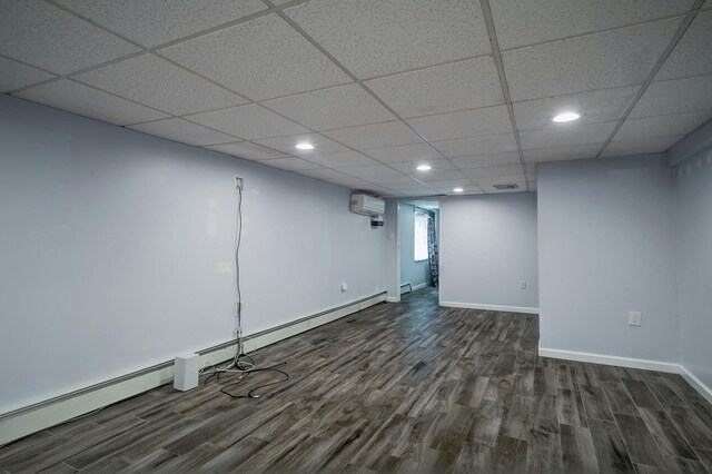 below grade area with a baseboard heating unit, an AC wall unit, recessed lighting, and dark wood-type flooring