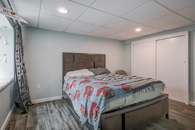 bedroom with a closet, wood finished floors, baseboards, and recessed lighting