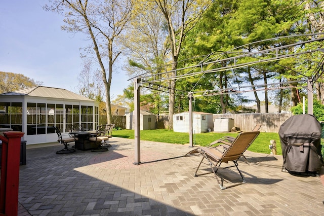 view of patio / terrace featuring a storage shed, a grill, a sunroom, a fenced backyard, and an outbuilding